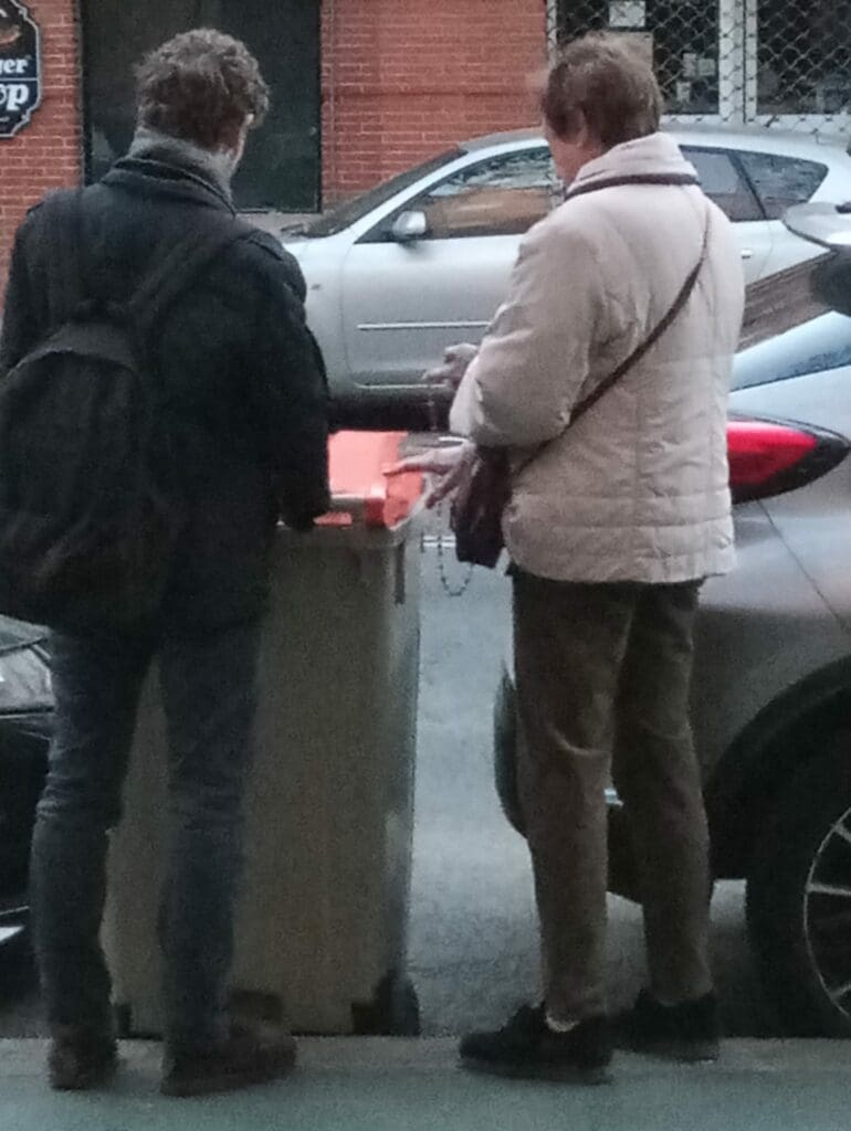 Dos personas rezan frente a un cubo de basura de la clínica
